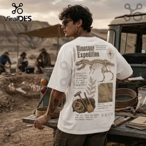Man wearing white t-shirt with brown T-Rex skeleton graphic, typography, and paleontology field tools in desert setting.!
