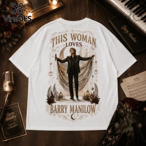 White t-shirt featuring a Barry Manilow graphic with gold celestial moons, stars, roses, and the text This Woman Loves.!