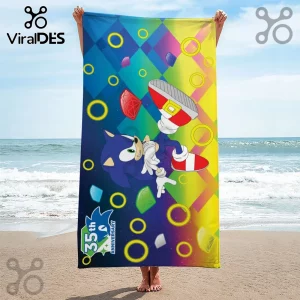 Sonic the Hedgehog beach towel with gradient blue to yellow background, gold rings, colorful chaos emeralds, and 35th logo.!