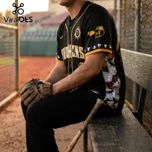Man wearing a black pinstripe baseball jersey with gold accents, Mudhens text, and Japanese-style cloud graphic patterns.!