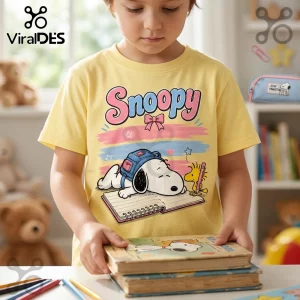 Child wearing a yellow short-sleeve t-shirt with a Snoopy and Woodstock graphic print with a book and school backpack.!