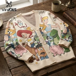 Cream knitted cardigan featuring printed Toy Story character graphics on a wooden table surface.!