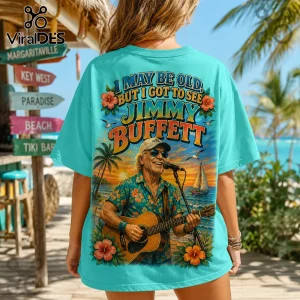 Jimmy Buffett I May Be Old Turquoise T-Shirt featuring a graphic of the singer playing guitar on a tropical beach.