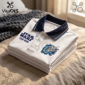 White polo shirt with a dark blue collar, featuring a Star Wars logo and a Millennium Falcon graphic on a bed.!