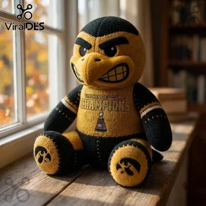 Iowa Hawkeyes Mascot Heroes Game Champions plush toy in black and gold fabric with a championship trophy graphic on the chest.