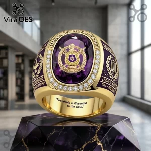 Omega Psi Phi Fraternity Embossed Ring featuring a large oval purple stone, gold band, and inlaid crystals on a marble base.