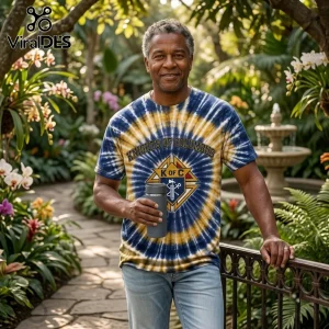 Knights of Columbus Premium Tie Dye T-Shirt in blue and yellow swirl pattern worn by a man holding a grey tumbler outdoors.