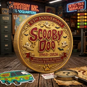 Scooby Doo Mystery Machine 63rd Anniversary gold coin with ghost icons, bats, and text on a wooden desk with a magnifying glass.