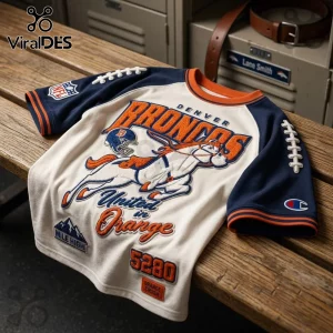 Denver Broncos 5280 Mile High embroidered shirt featuring team mascot, blue sleeves, and white torso on a wooden bench.