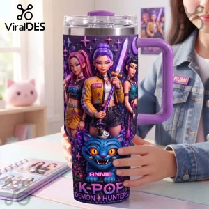 K-Pop Demon Hunters Purple 40oz Tumbler with Handle featuring anime-style girls, swords, and a blue cat demon character.