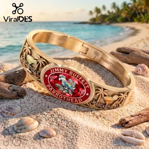 Jimmy Buffett Margaritaville gold tone engraved bracelet with a red center stone and palm tree details on sandy beach.