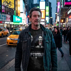 Peter Cullen Optimus Prime 1941-2026 Tribute T-Shirt worn by a man in a denim jacket standing on a busy city street.