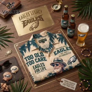 NFL Philadelphia Eagles Mascot Hawaiian Shirt in beige with palm trees and typography on a wooden table with team gear.
