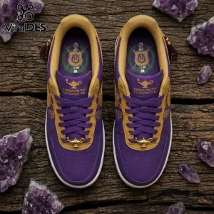 Omega Psi Phi Fraternity Air Force 1 shoes in purple and gold leather featuring gold lamp dubraes on a wooden background.