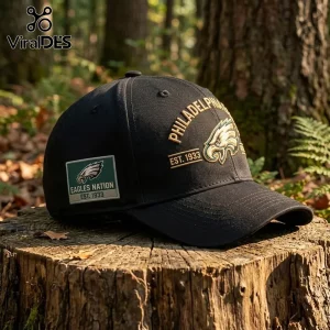 NFL Philadelphia Eagles Fly Eagles Fly Baseball Cap in black with gold embroidery and a side patch on a wooden tree stump.