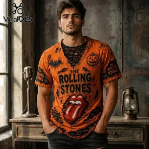 The Rolling Stones Orange Distressed V-Neck Shirt with pumpkin, bat, and tongue graphics on a man in a rustic studio.