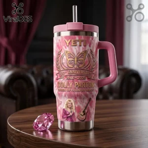 Dolly Parton 80th Anniversary Pink Tie-Dye YETI Tumbler with butterfly graphic, guitar, and portrait on a wooden table.
