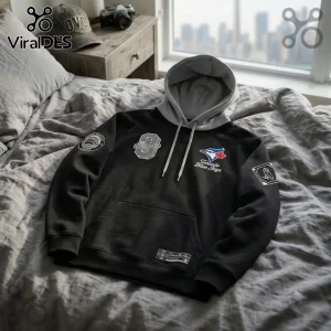 Toronto Blue Jays x OVO Black Two-Tone Hoodie featuring grey hood, embroidered team logo, and patches on a rumpled bed.