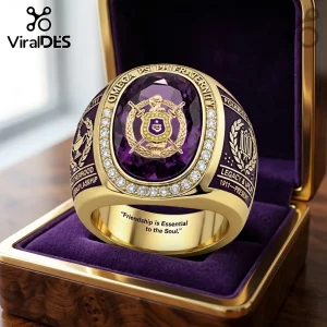 Omega Psi Phi Fraternity Embossed Ring featuring a large purple oval stone, gold crest, and clear accent stones in a box.