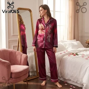 Marilyn Monroe 100th Anniversary burgundy satin pajama set featuring a portrait graphic and script text in a bedroom.