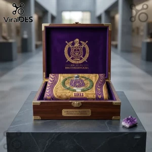 Omega Psi Phi 1911 gold and purple shirt displayed in a wooden display box featuring fraternity crests and embroidery.