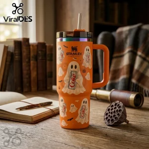Orange Ghost Diet Coke 40oz Stanley Tumbler with spooky ghost patterns and Diet Coke cans on a wooden desk with books.