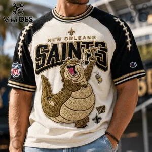 New Orleans Saints Mascot Embroidered Shirt featuring an alligator holding a trumpet on a black and cream raglan jersey.