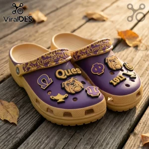 Omega Psi Phi Mascot Slip On Clogs With Charms in purple and gold with bulldog, lamp, and 1911 iconography on wood floor.