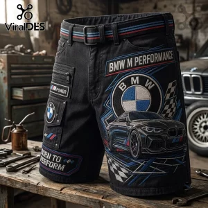 BMW M Performance black cargo shorts with M logo branding, embroidered car graphics, and a striped belt on a workbench.
