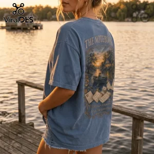 The Notebook Soft Love Era blue t-shirt with a vintage graphic print of a couple in a rowboat at sunset on the back.
