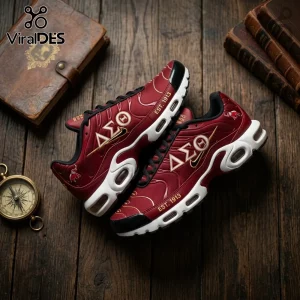 Delta Sigma Theta 1913 Crimson Air Max Plus shoes with Greek letters, elephant icons, and white soles on rustic wood.