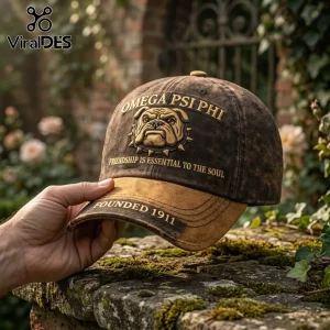 Omega Psi Phi 1911 Bulldog Distressed Baseball Cap with brown acid-washed fabric, gold embroidery, and an ivy garden backdrop.