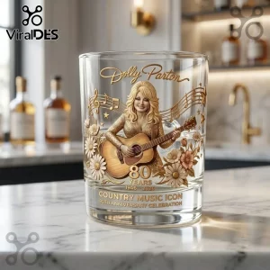 Dolly Parton 80th Anniversary Gold Whiskey Glass with a 3D relief of Dolly playing guitar, music notes, and daisies.