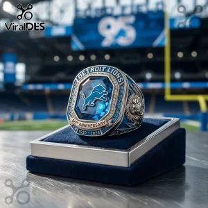 Detroit Lions 96th Anniversary Blue Gem Ring featuring a central sapphire stone, metallic lion relief, and stadium backdrop.