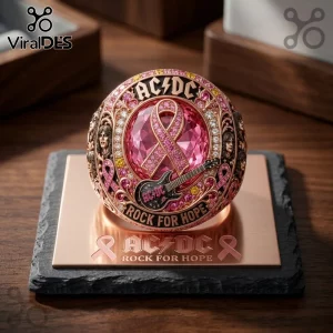 AC/DC Rock For Hope Breast Cancer Awareness Ring featuring a pink ribbon gem, gold band, guitar motif, and band portraits.