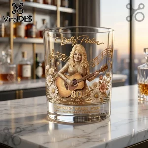 Dolly Parton 80th Anniversary Gold Whiskey Glass featuring a 3D relief of the singer playing guitar with floral accents.