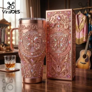 Dolly Parton Rose Gold Butterfly Rhinestone Stanley Tumbler with ornate guitar emblems and crystals on a wooden table.
