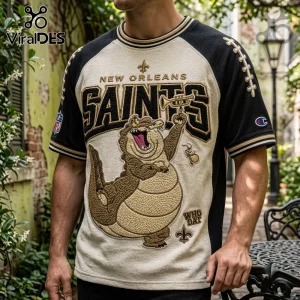 New Orleans Saints mascot embroidered shirt featuring a cartoon alligator playing a trumpet on a cream and black jersey.