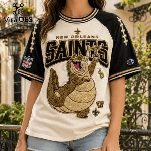 New Orleans Saints Mascot Embroidered Shirt featuring an alligator playing a trumpet on a cream and black raglan jersey.