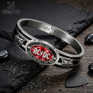 AC/DC For Those About To Rock Bracelet featuring a silver band, red center stone, and cannon emblems on a dark background.