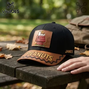 Peanuts Snoopy Red Doghouse Custom Name Baseball Cap featuring a leather patch on a black hat sitting on a wooden bench.
