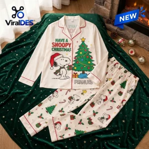 Front view of white Snoopy Christmas Satin Pajamas Set with festive tree graphic laid on green blanket.