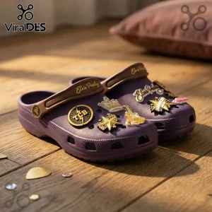 Elvis Presley Purple Crocband Clog With Charms featuring TCB logo, gold guitar, and crown pins on a wooden floor.