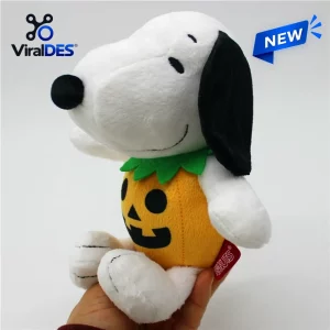 Side angle of a plush dog wearing an orange pumpkin suit with a green collar, a Snoopy Halloween 2026 pumpkin plush toy.