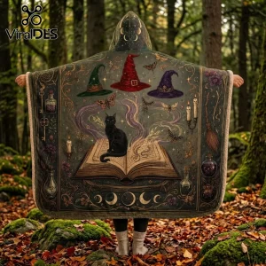 Witchcraft Black Cat Illustrated Hooded Blanket featuring a feline on a spellbook, wizard hats, and candles in a forest.