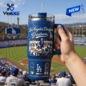Hand holding blue Stanley Tumbler featuring Los Angeles Dodgers Greatness text and team graphics.