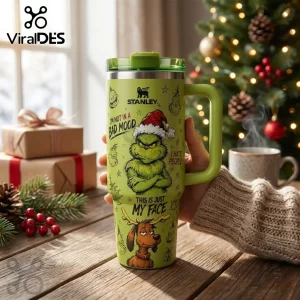 Stanley The Grinch Green 40oz Flowstate Tumbler featuring Grinch illustrations and quotes on a wooden table.