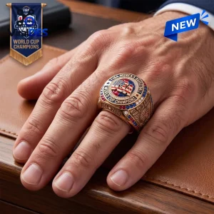 USA Basketball FIBA Women's World Cup 2026 Ring in gold with red and blue gemstone accents worn on a man's finger.
