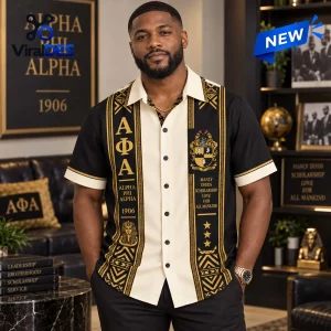 Front view of a man wearing a black and cream Alpha Phi Alpha Fraternity Premium Hawaiian Shirt with gold graphic designs.