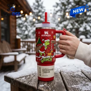 Hand holding a red Dr. Seuss The Grinch Stanley Quencher Tumbler outdoors in a snowy winter setting.